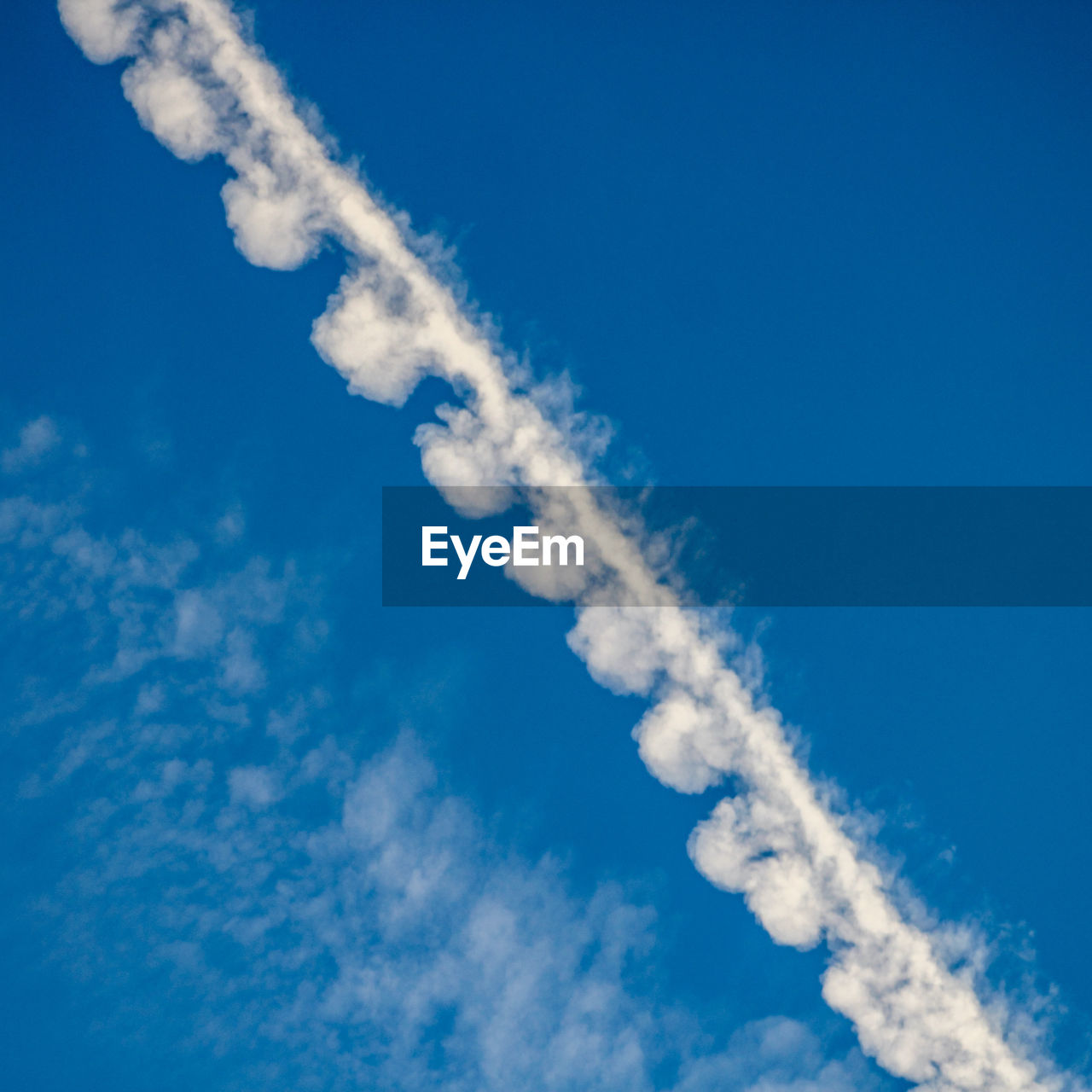 Fluffy chemtrail or contrail overhead against blue sky
