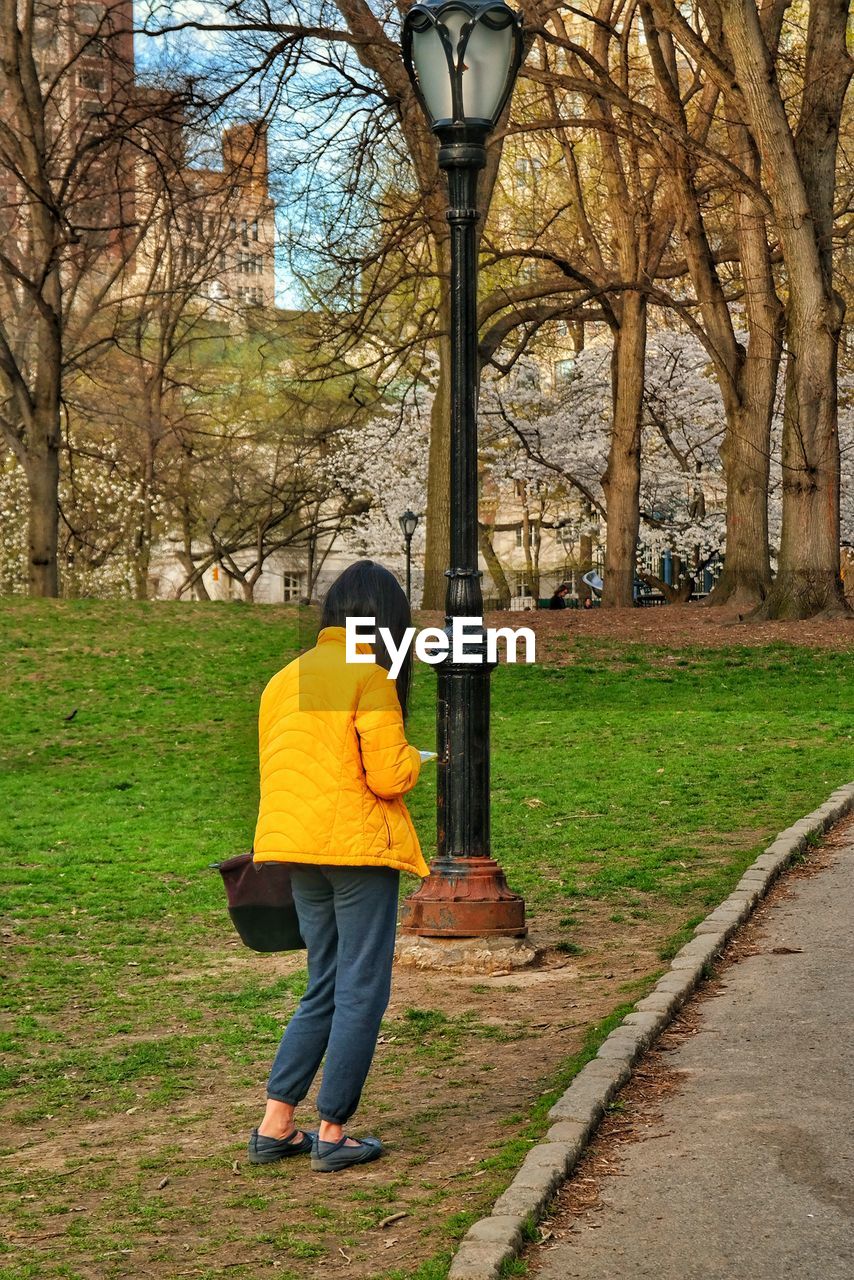 FULL LENGTH REAR VIEW OF WOMAN WALKING ON FOOTPATH IN PARK