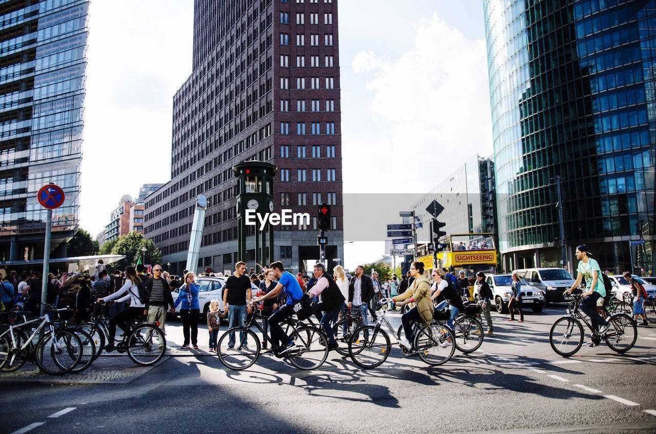 People riding bicycles on street against buildings in city