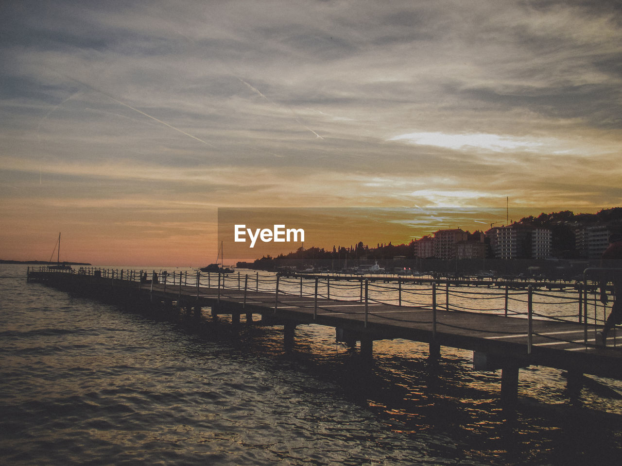 Scenic view of sea by buildings against sky during sunset