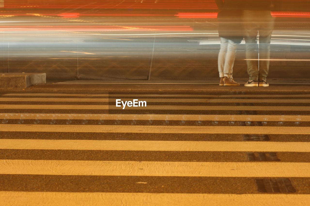 Blurry light trails and couple standing at zebra crossing