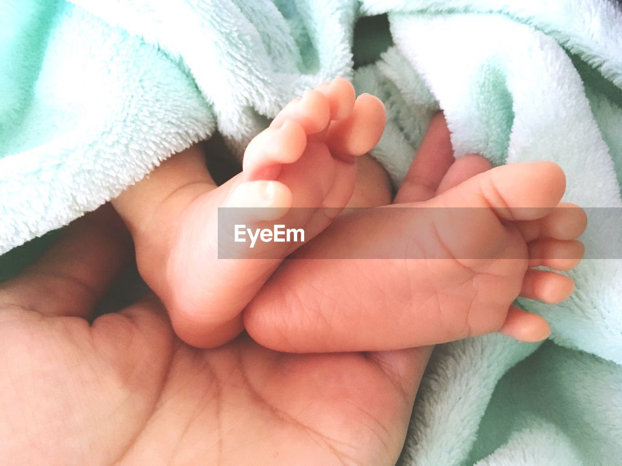 Cropped image of mother holding baby feet wrapped in towel