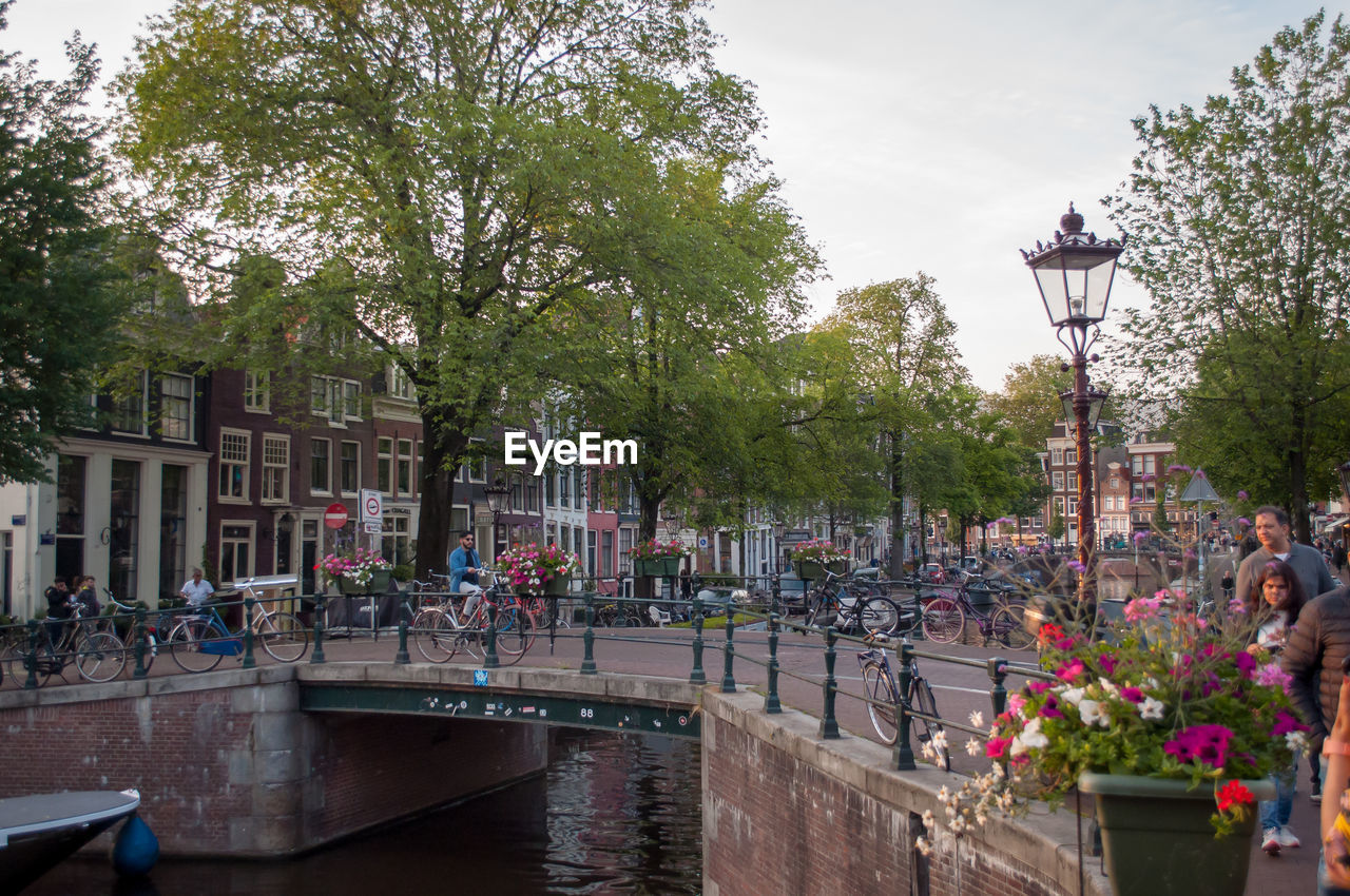 People on street by canal against sky