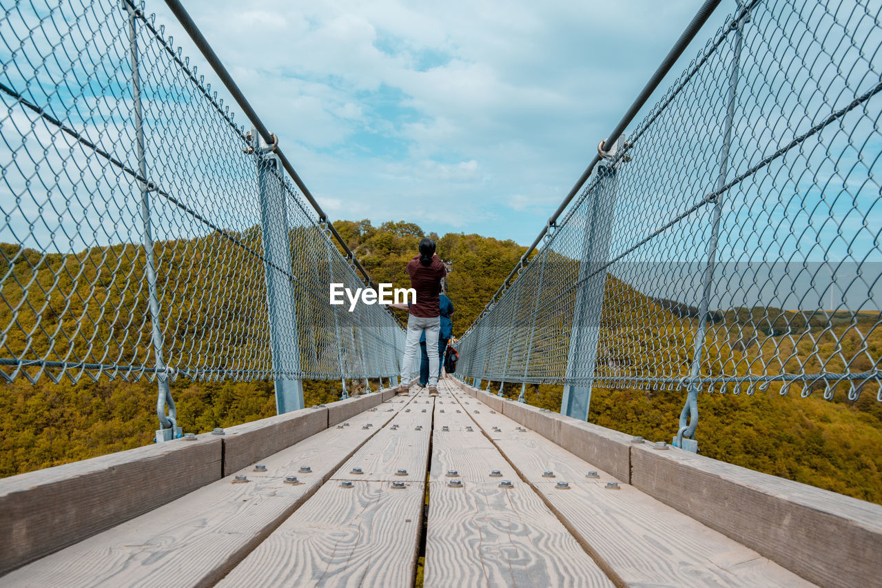 Rear view of man standing on footbridge