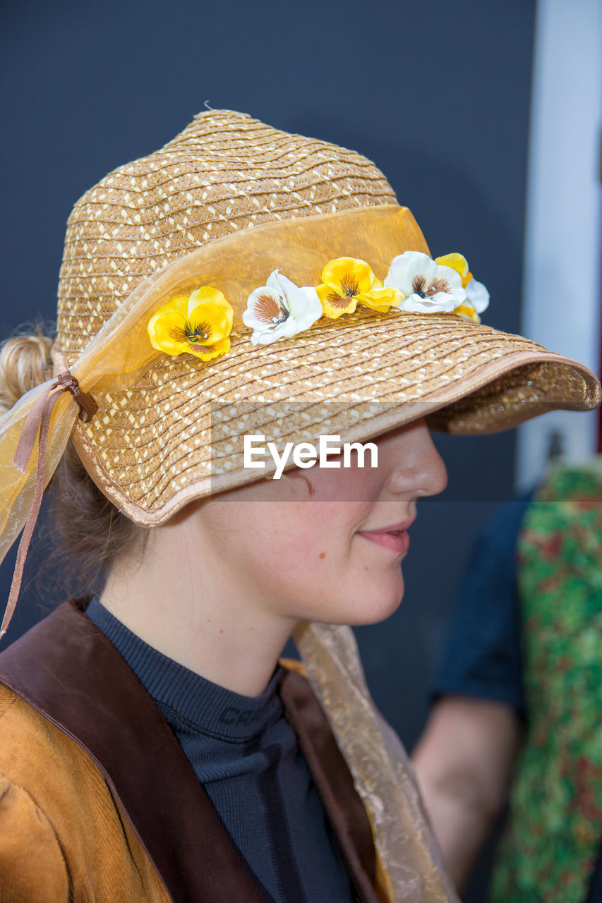 CLOSE-UP PORTRAIT OF YOUNG WOMAN HOLDING HAT ON PAPER