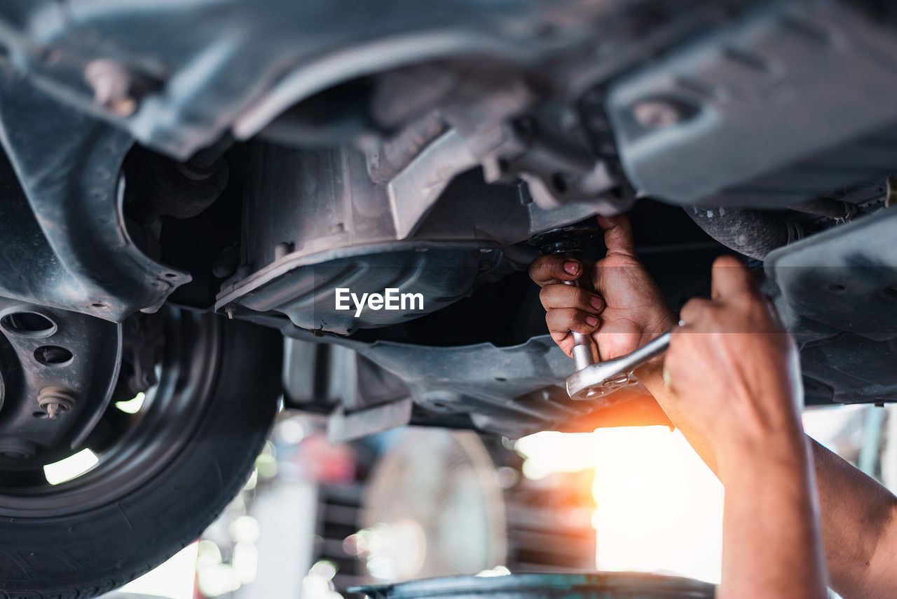 cropped image of man repairing car engine