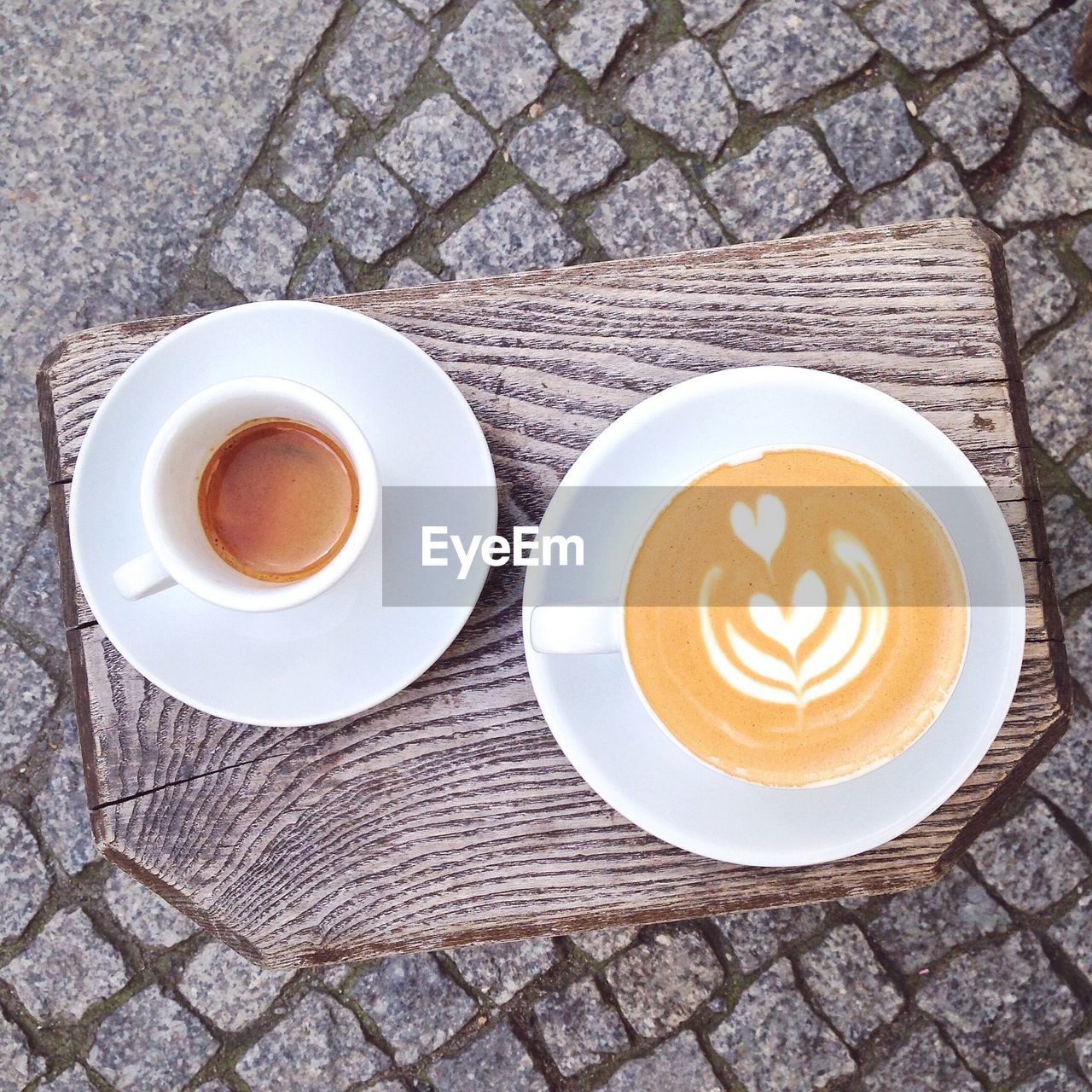 High angle view of cappuccino on cutting board over footpath