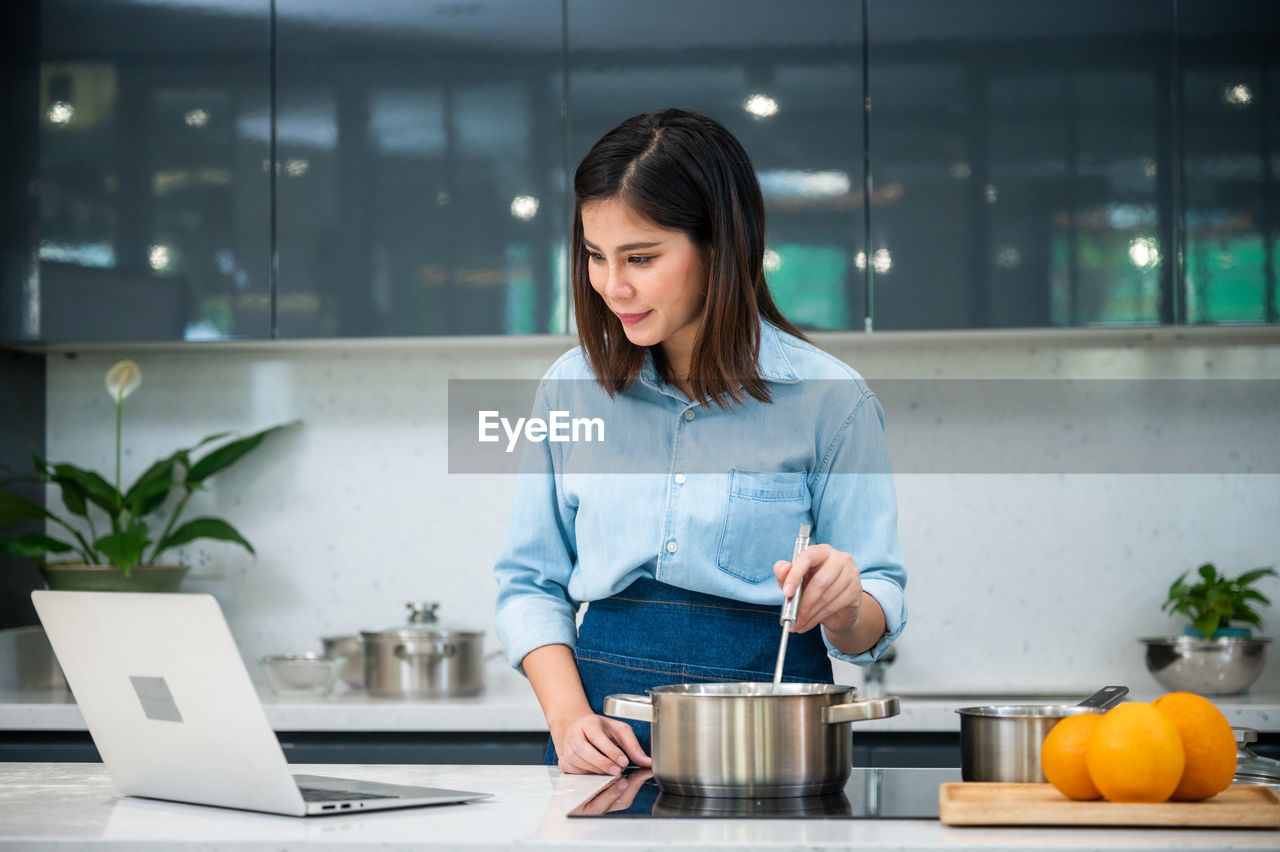 FULL LENGTH OF WOMAN WORKING WITH LAPTOP IN RESTAURANT