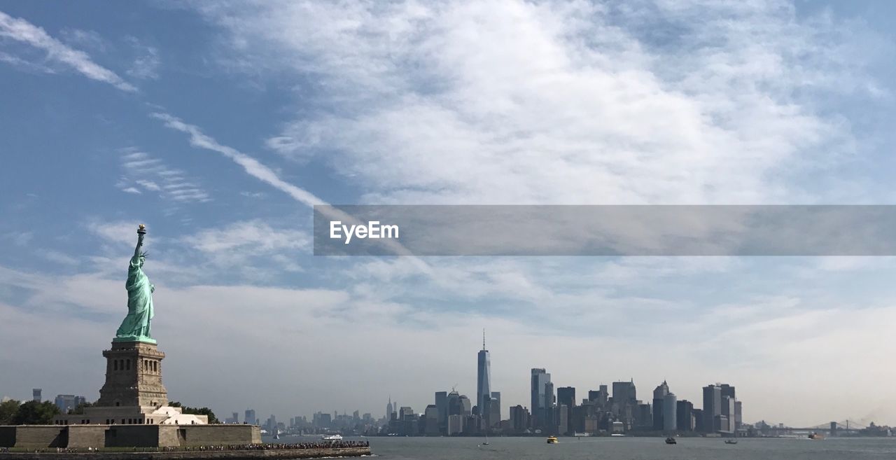 Statue of liberty against cloudy sky in city