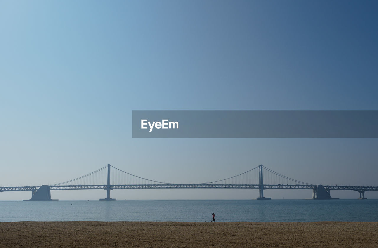 Bridge over sea against clear blue sky