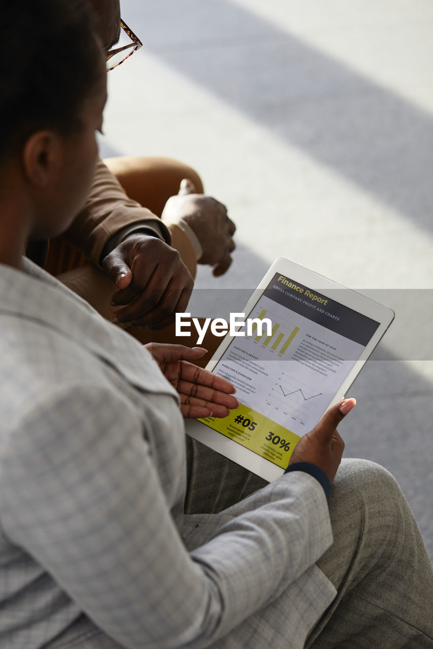 Businesswoman discussing financial report on tablet pc with colleague in office