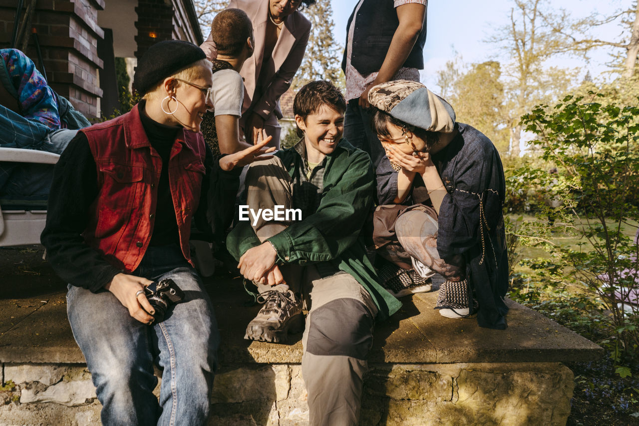 Happy friends of lgbtq community enjoying together while sitting on porch at sunny day
