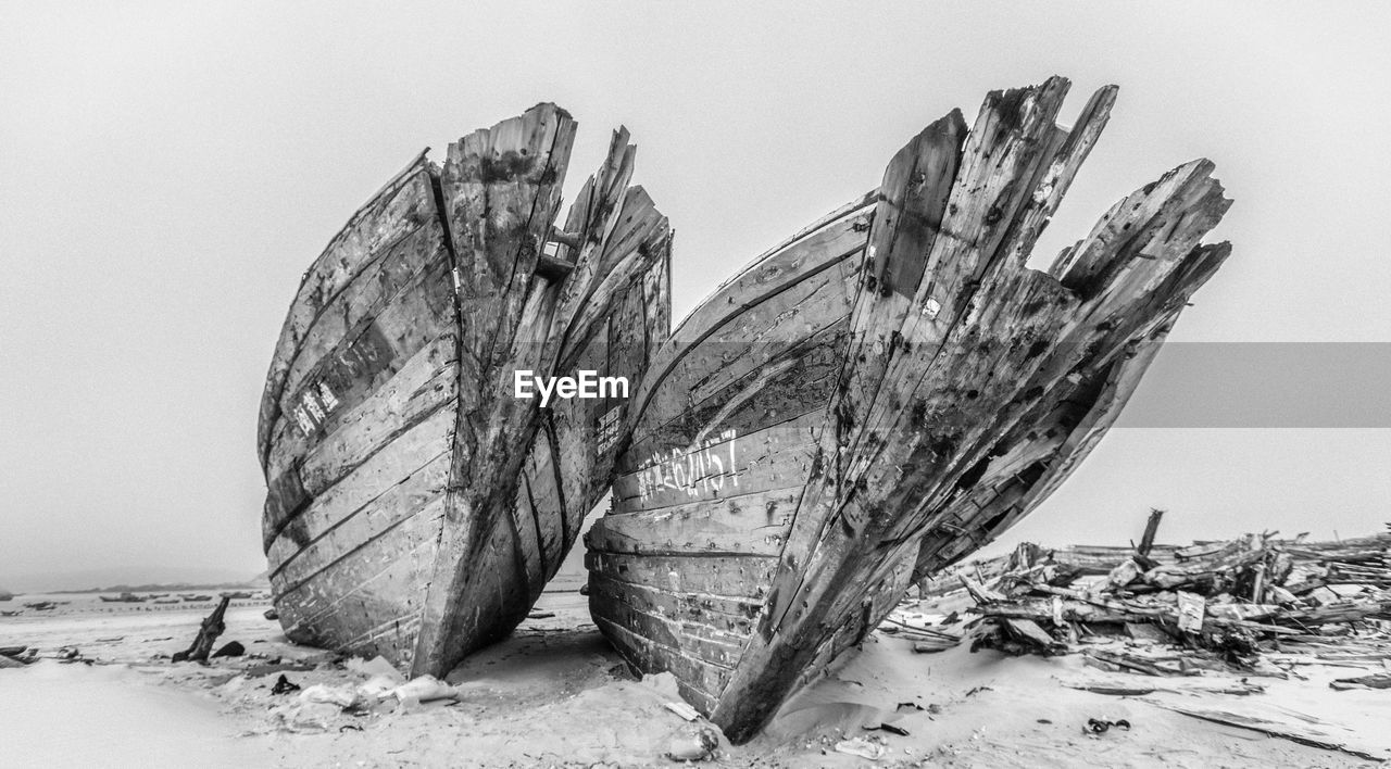 Low angle view of abandoned boats on beach against clear sky