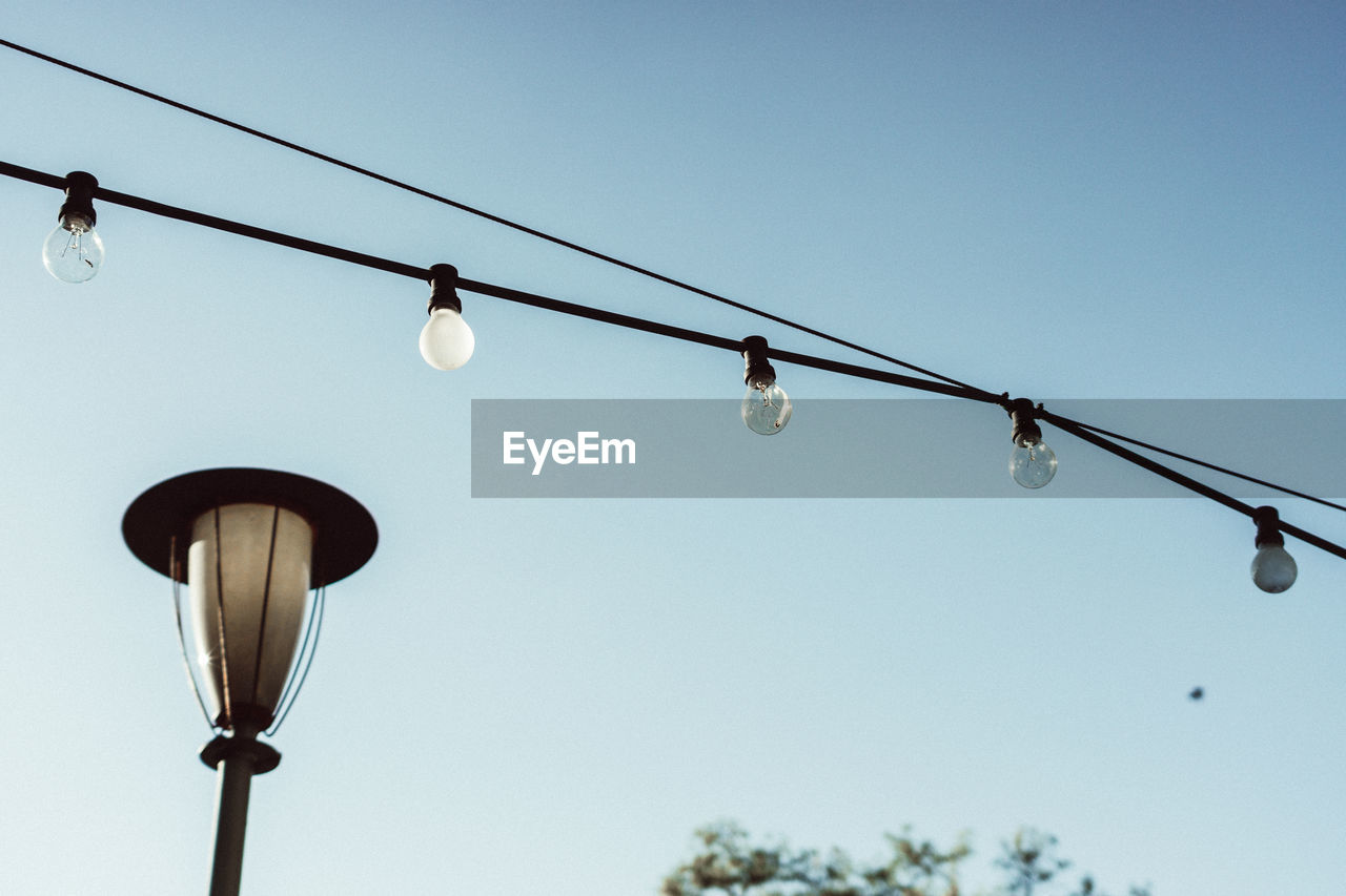 Low angle view of string light against clear sky