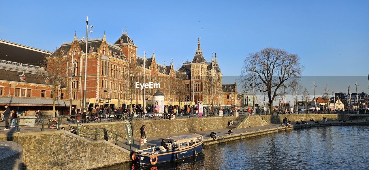 buildings by river against clear blue sky