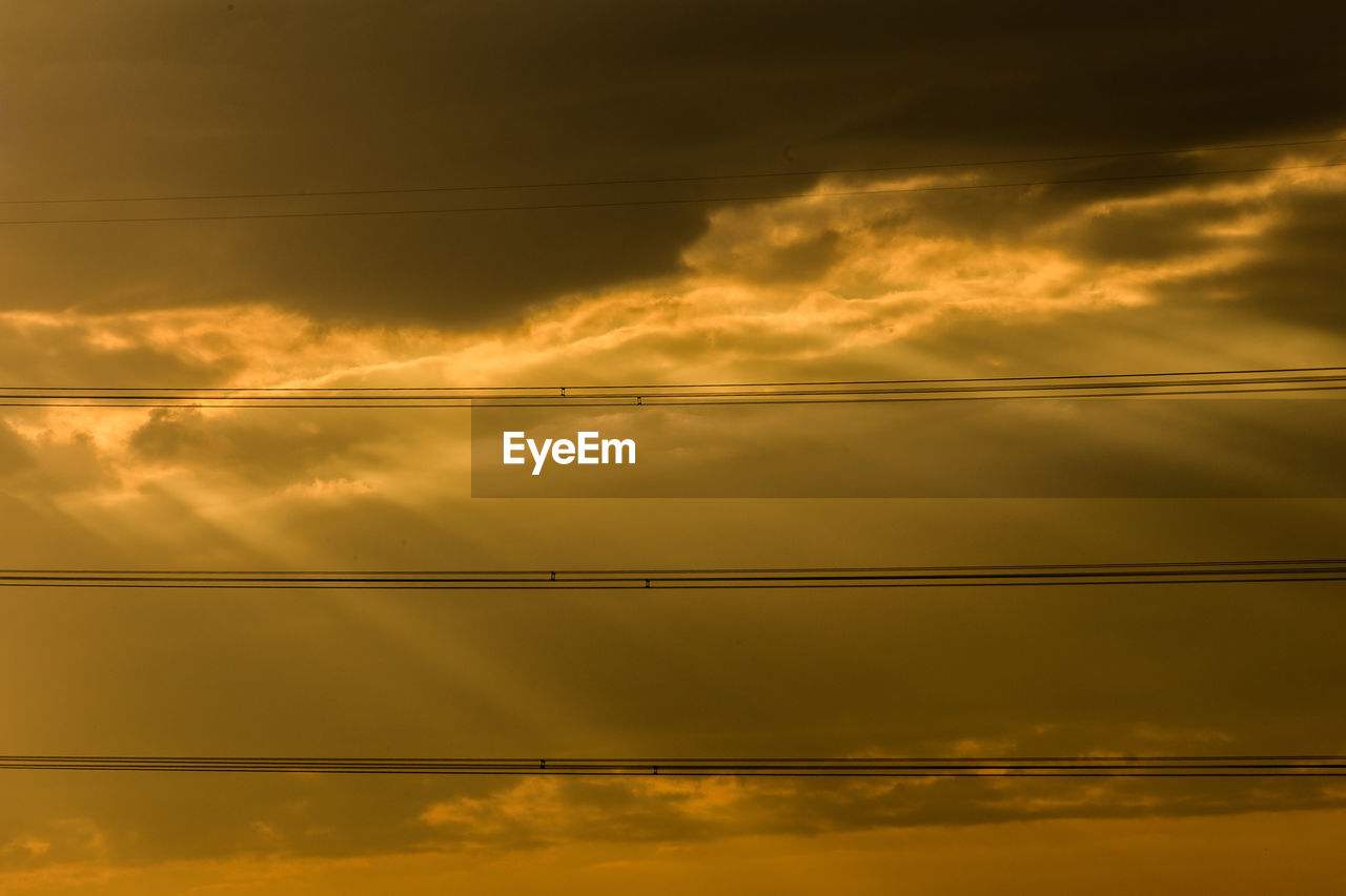 LOW ANGLE VIEW OF POWER LINES AGAINST ORANGE SKY