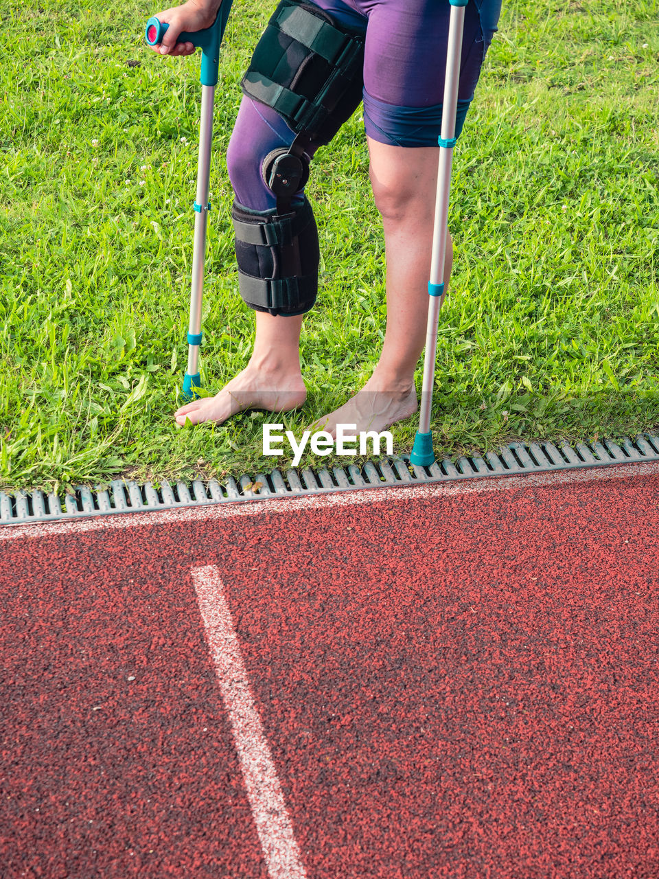 Walk by crutches. woman runner got sports injury running on stadium trail