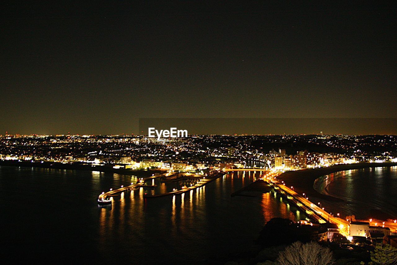 ILLUMINATED CITY BY RIVER AGAINST SKY