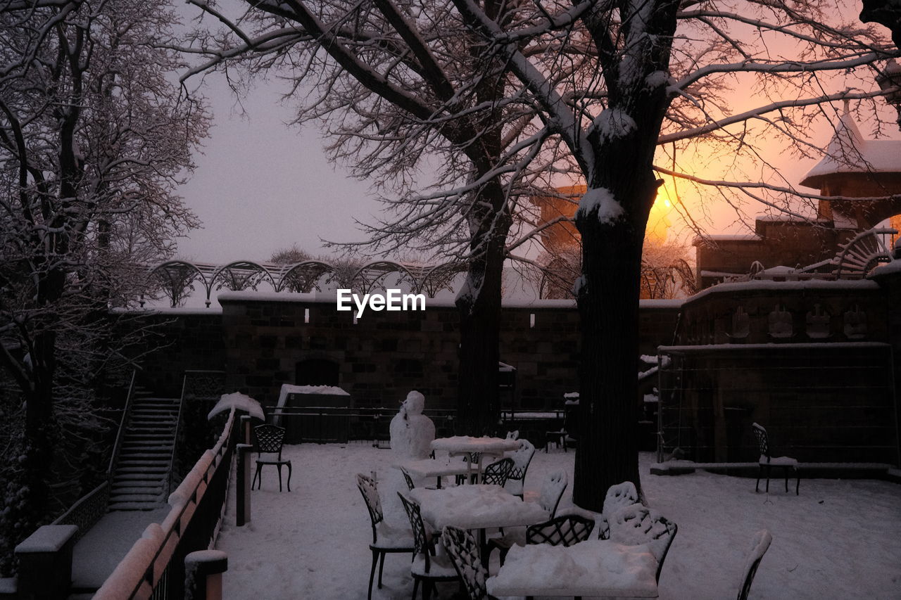 BARE TREE AND BUILDINGS AGAINST SKY DURING WINTER AT DUSK