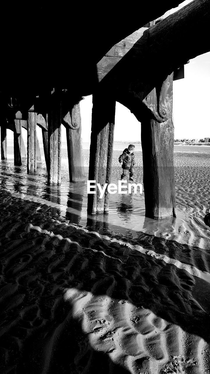 Boy playing by old pier at beach