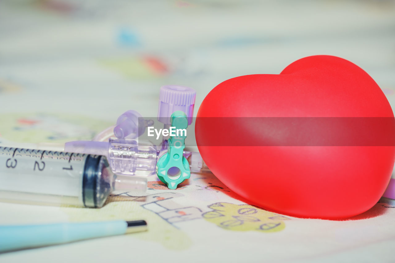 Close up of heart shape balloon with medical equipment on table