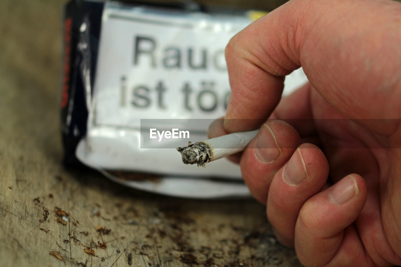 Close-up of hand smoking cigarette at table