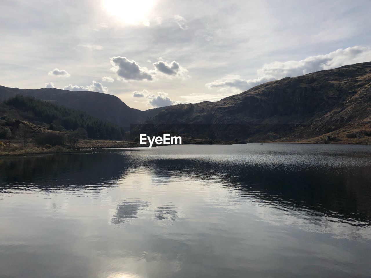 Scenic view of lake by mountains against sky