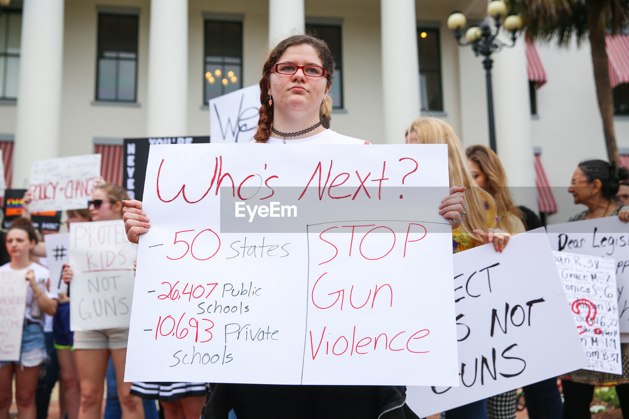 CLOSE-UP OF WOMAN WITH TEXT IN FRONT OF SIGN