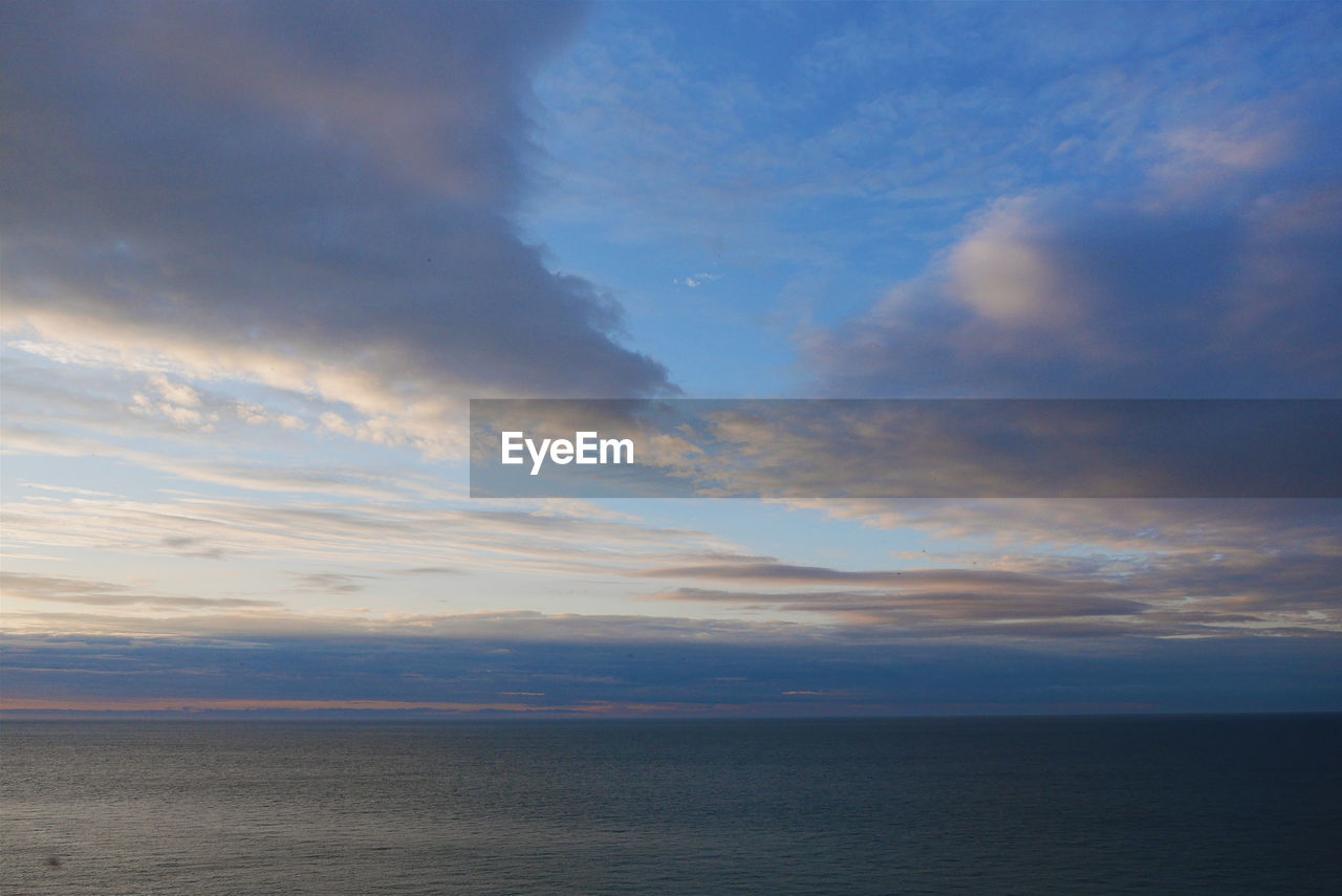 SCENIC VIEW OF SEA AGAINST CLOUDY SKY DURING SUNSET