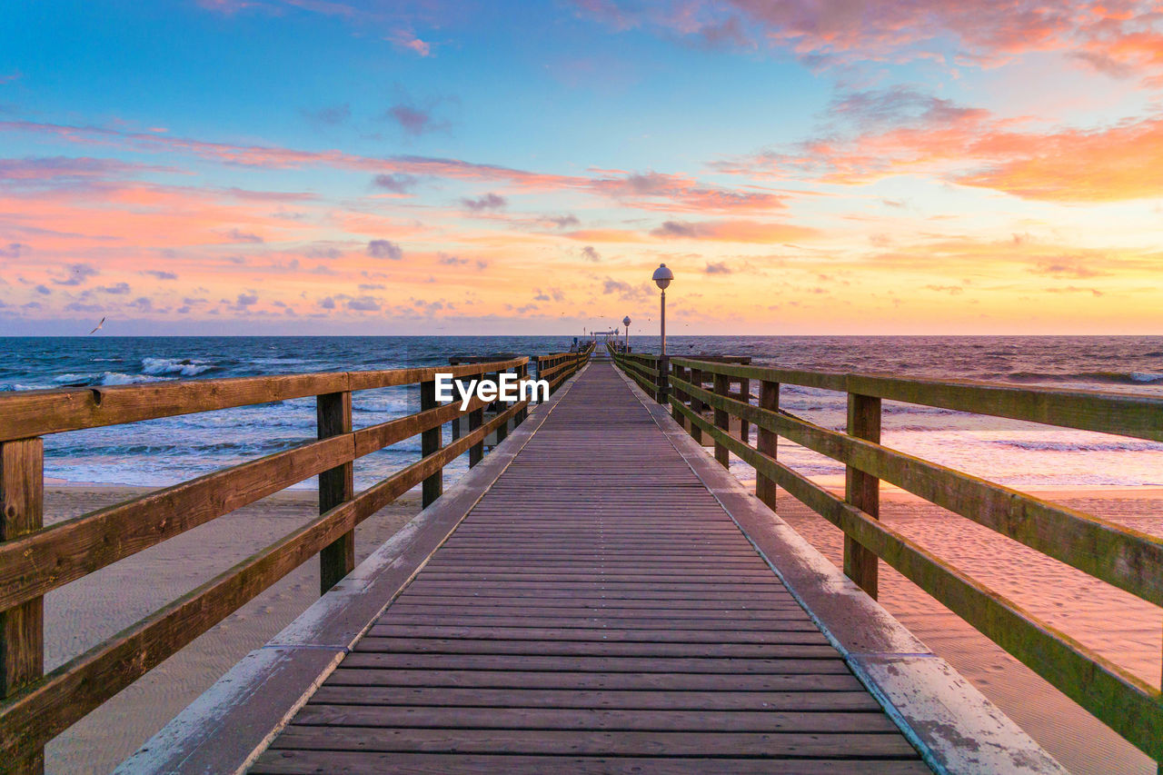 Pier over sea against sky during sunset