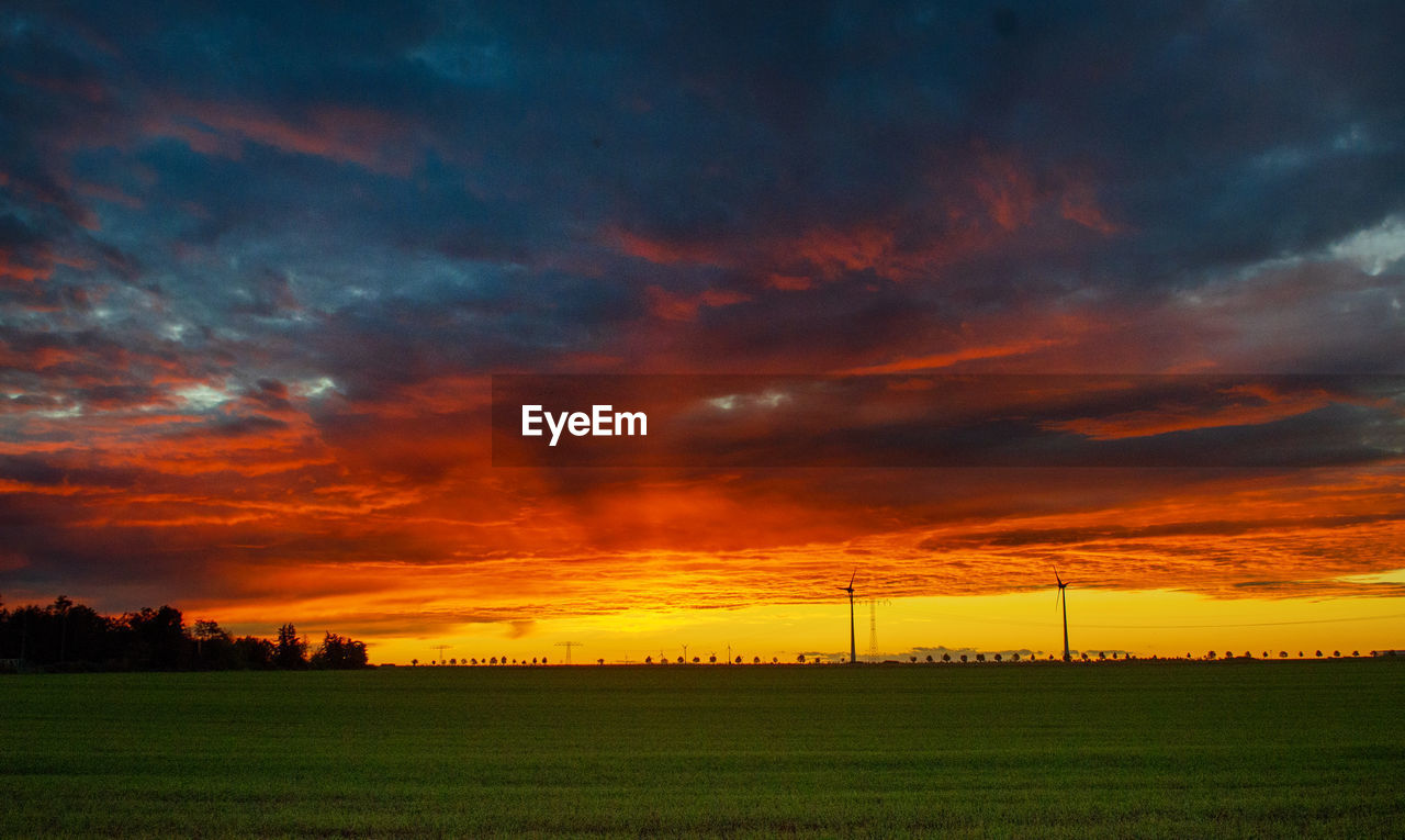 scenic view of field against cloudy sky during sunset