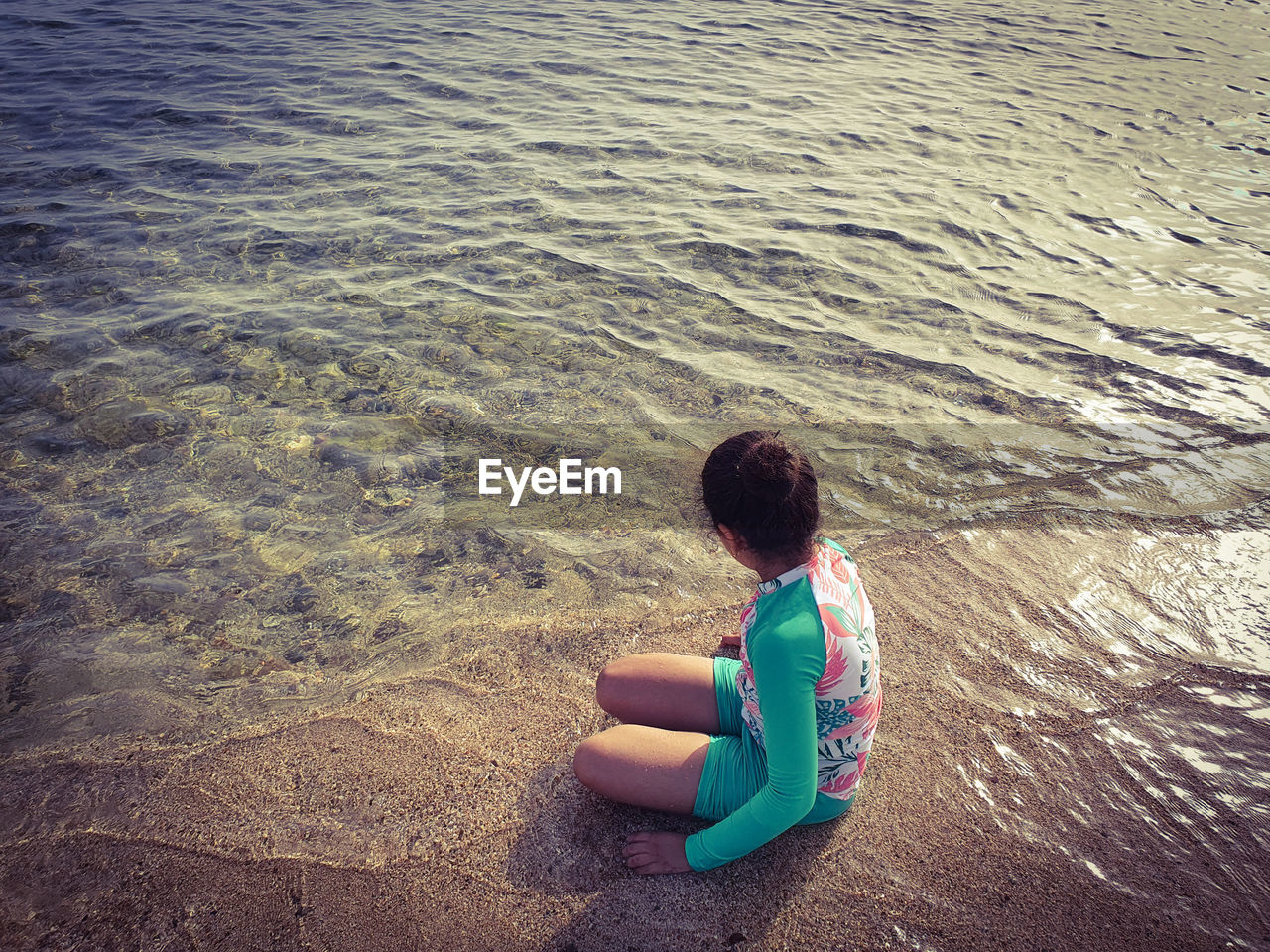 HIGH ANGLE VIEW OF BOY SITTING ON SHORE