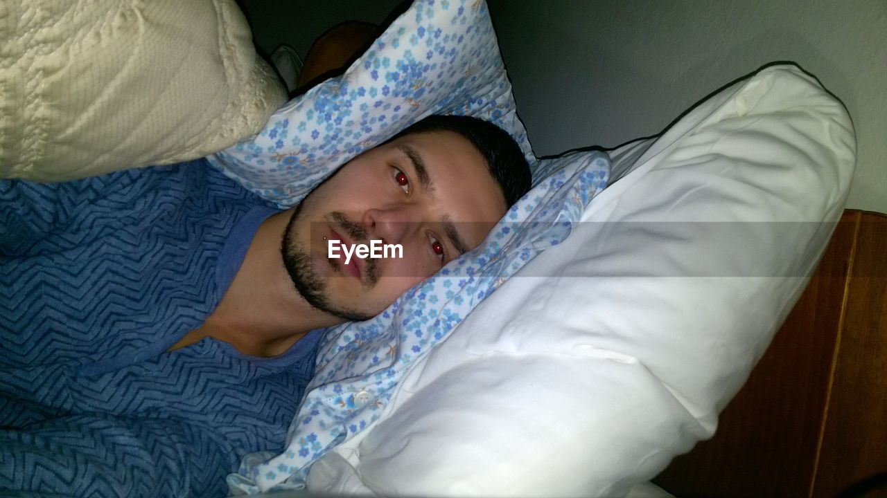 HIGH ANGLE VIEW OF MAN SLEEPING IN BED