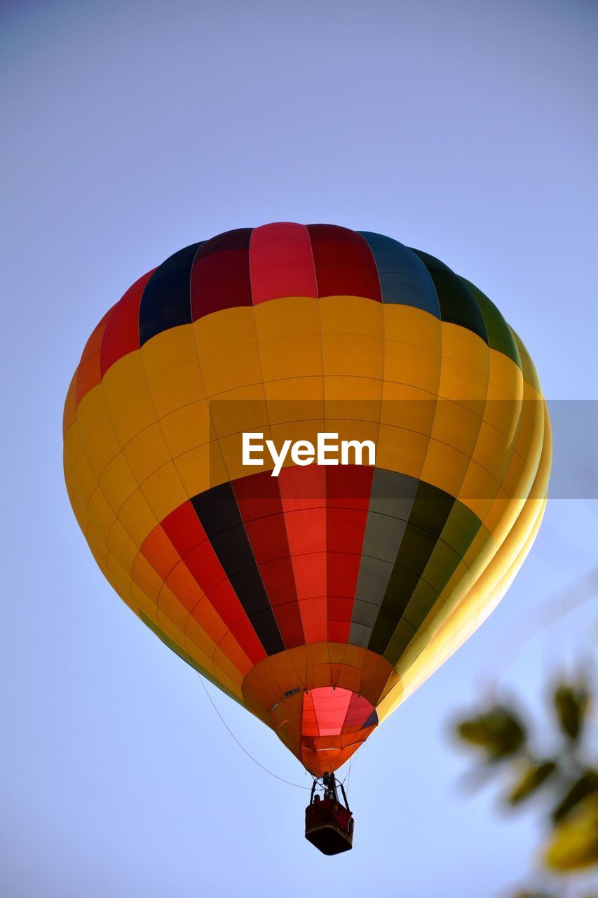 Low angle view of hot air balloon flying in clear blue sky