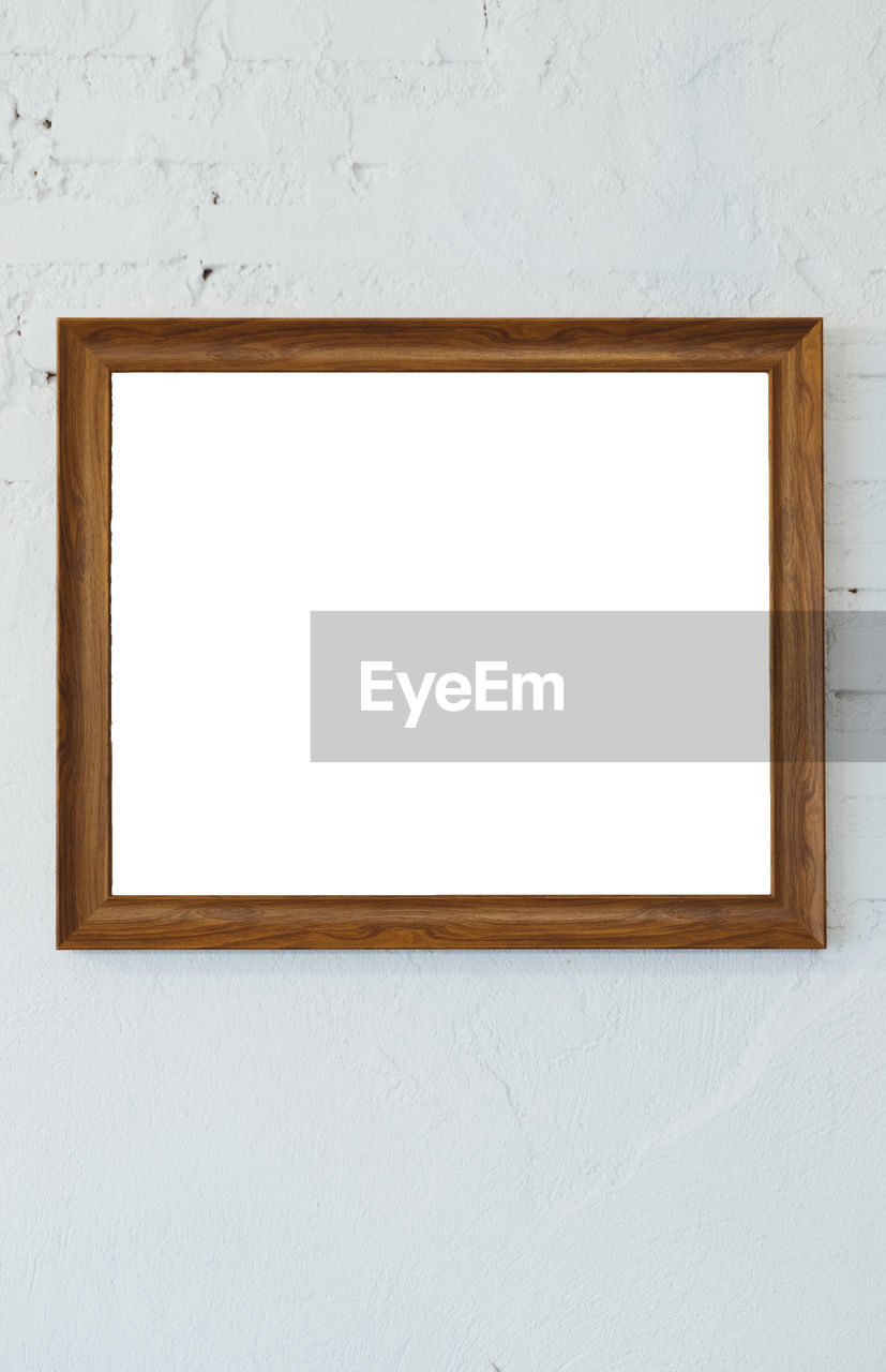 Wooden photo frame on the white room wall inside the building