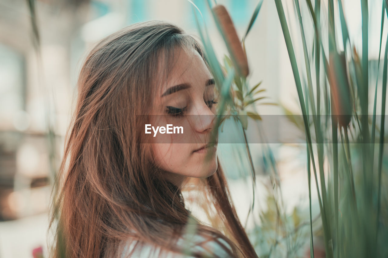 Woman with eyes closed standing by plants