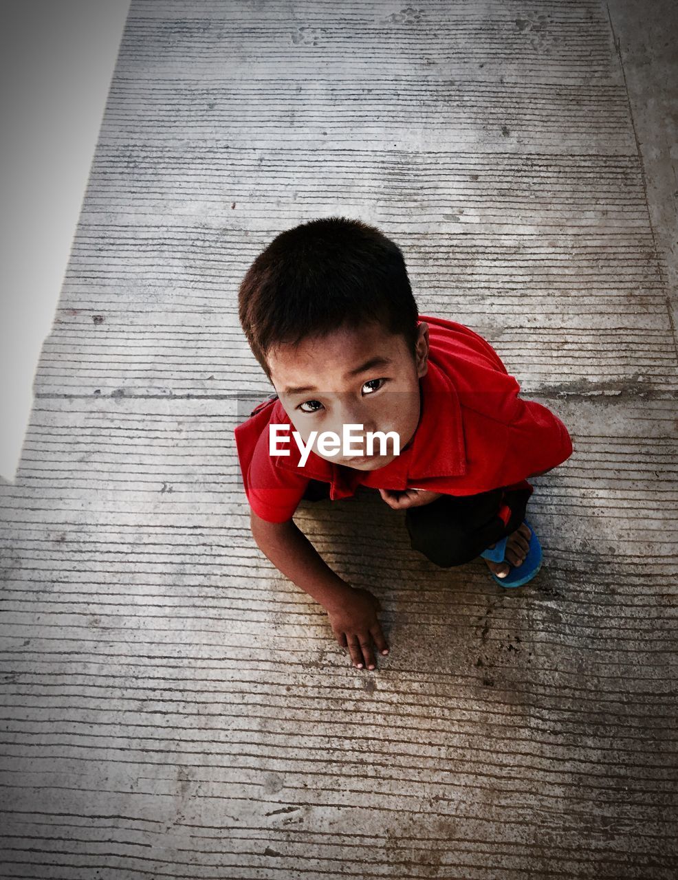 PORTRAIT OF CUTE BOY ON HARDWOOD FLOOR AGAINST WALL