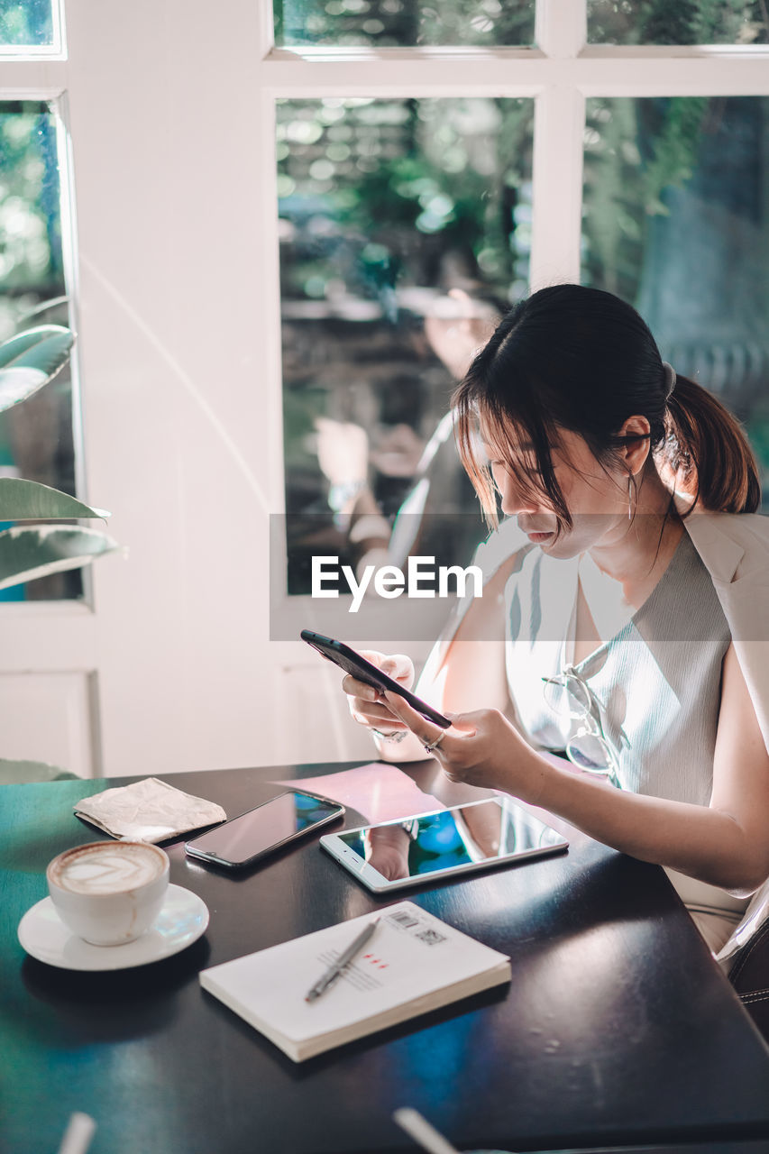 Woman using phone sitting at cafe