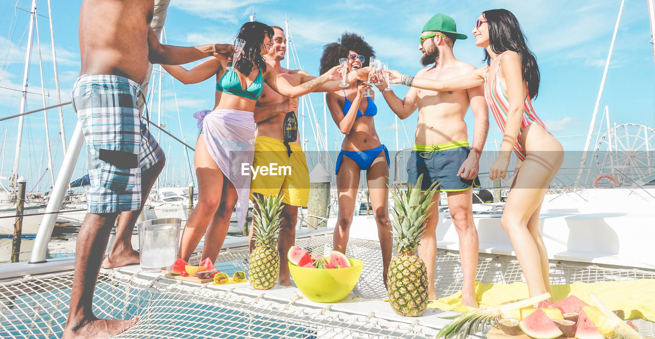 Smiling friends raising toast while standing in ship