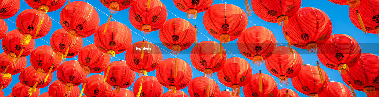 Low angle view of lantern hanging in row against sky