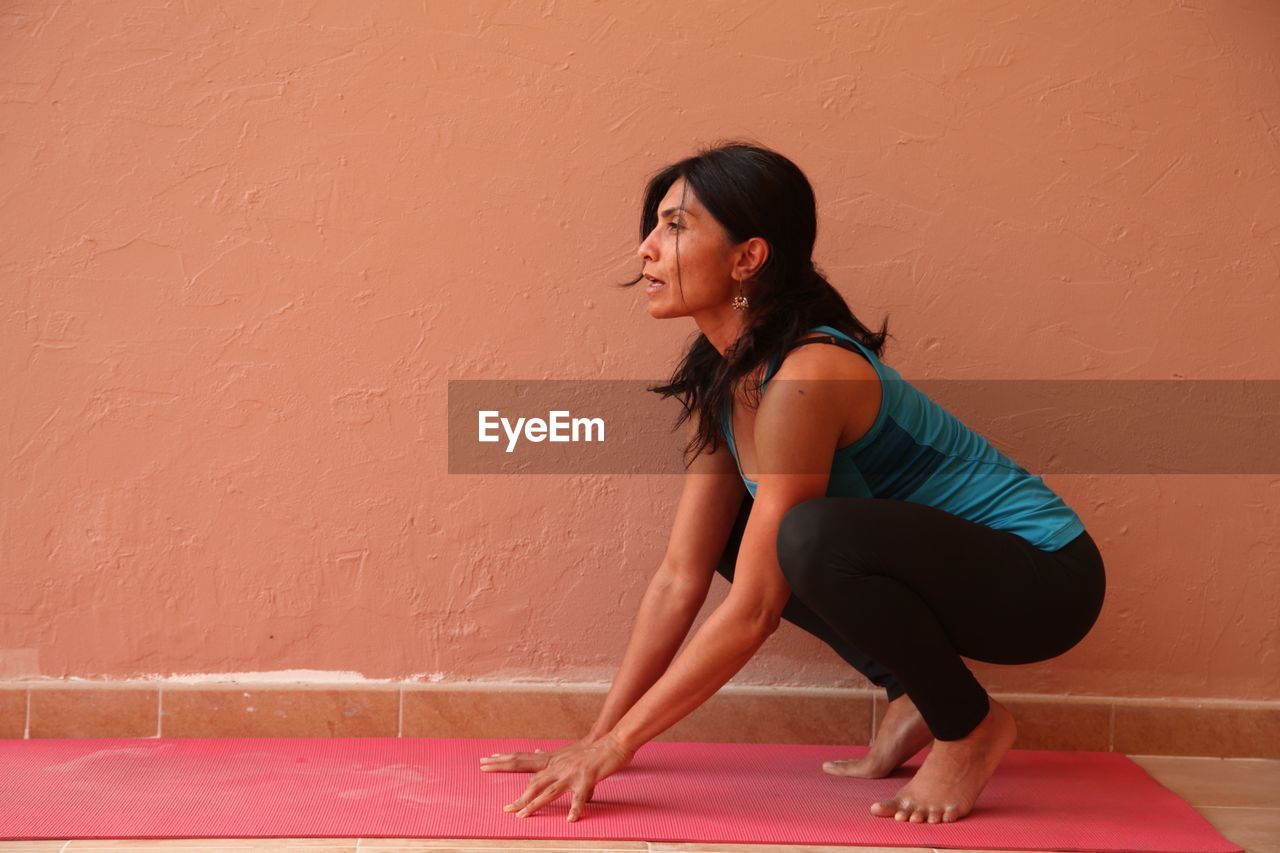 Young woman crouching by wall