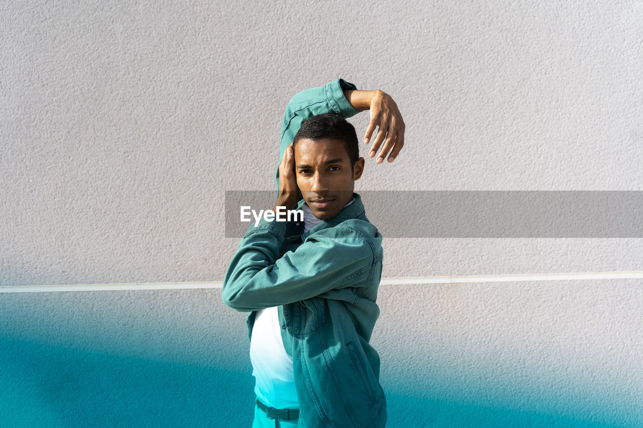 Young man dancing while standing against multi colored wall