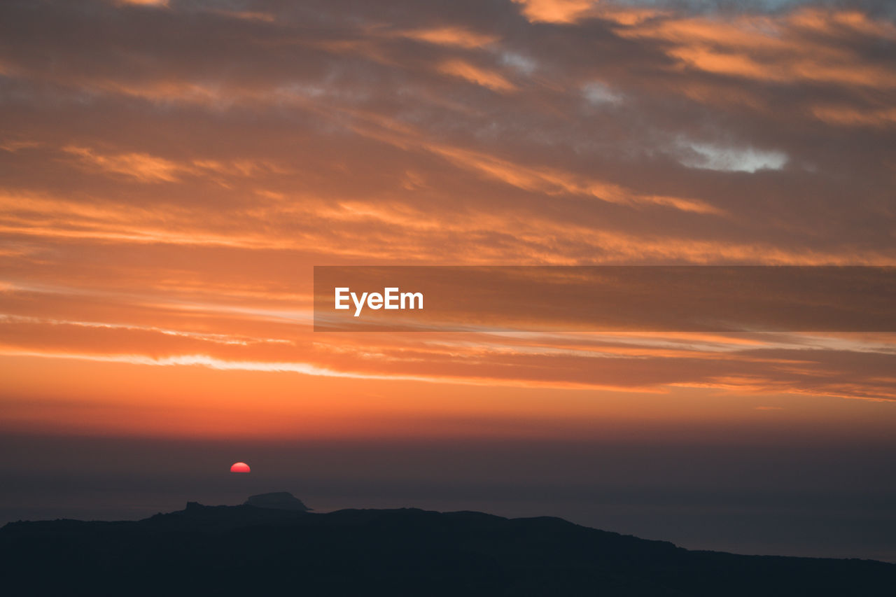 Low angle view of silhouette mountain against sky during sunset. fira, santorini 