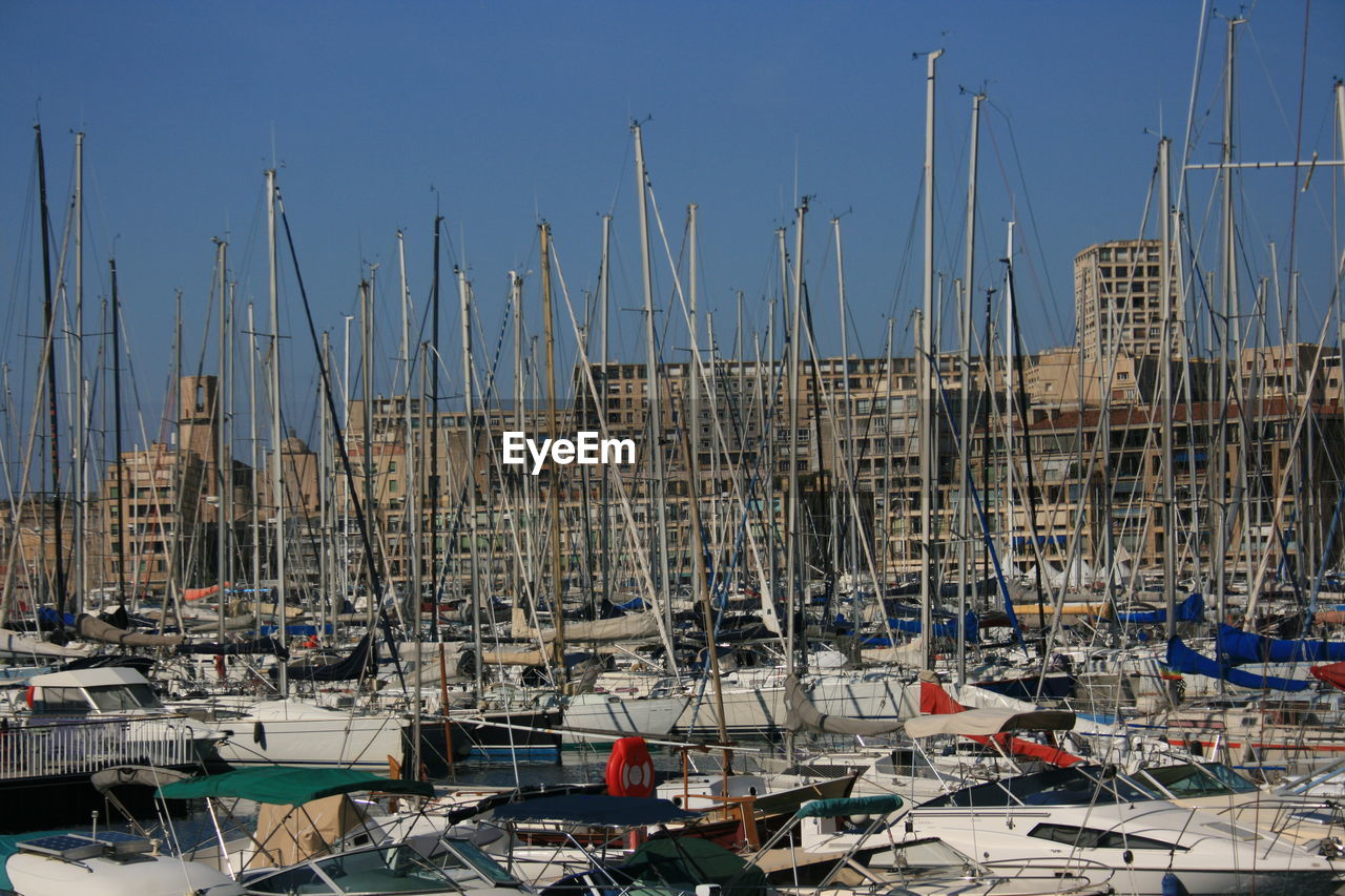 SAILBOATS IN HARBOR AGAINST BUILDINGS