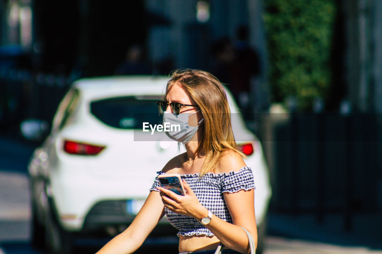 WOMAN HOLDING UMBRELLA WHILE STANDING ON CAR