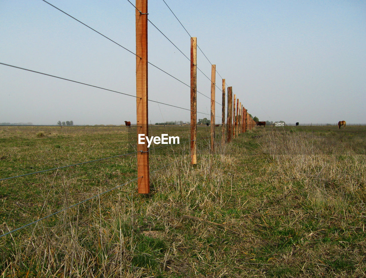 Wooden fence on field against clear sky