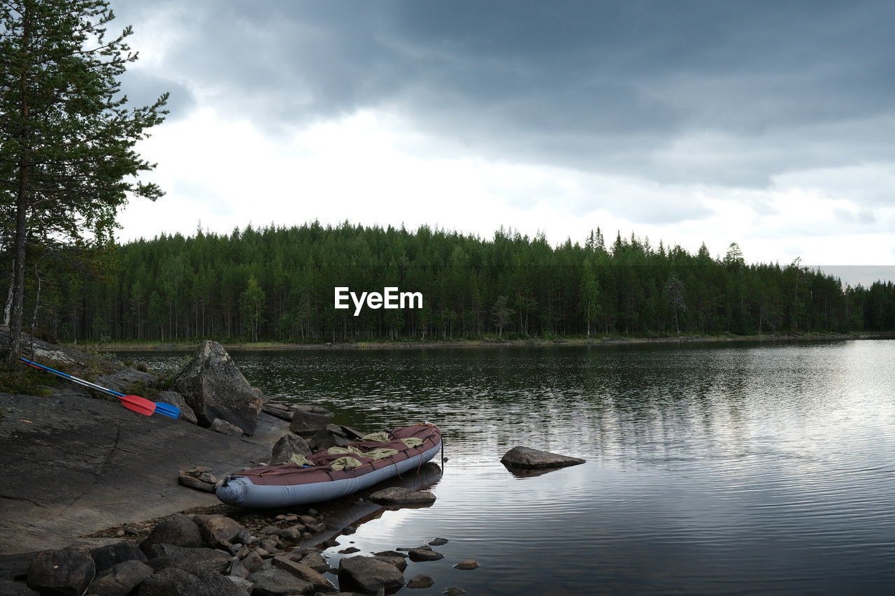 BOATS MOORED ON RIVERBANK AGAINST SKY