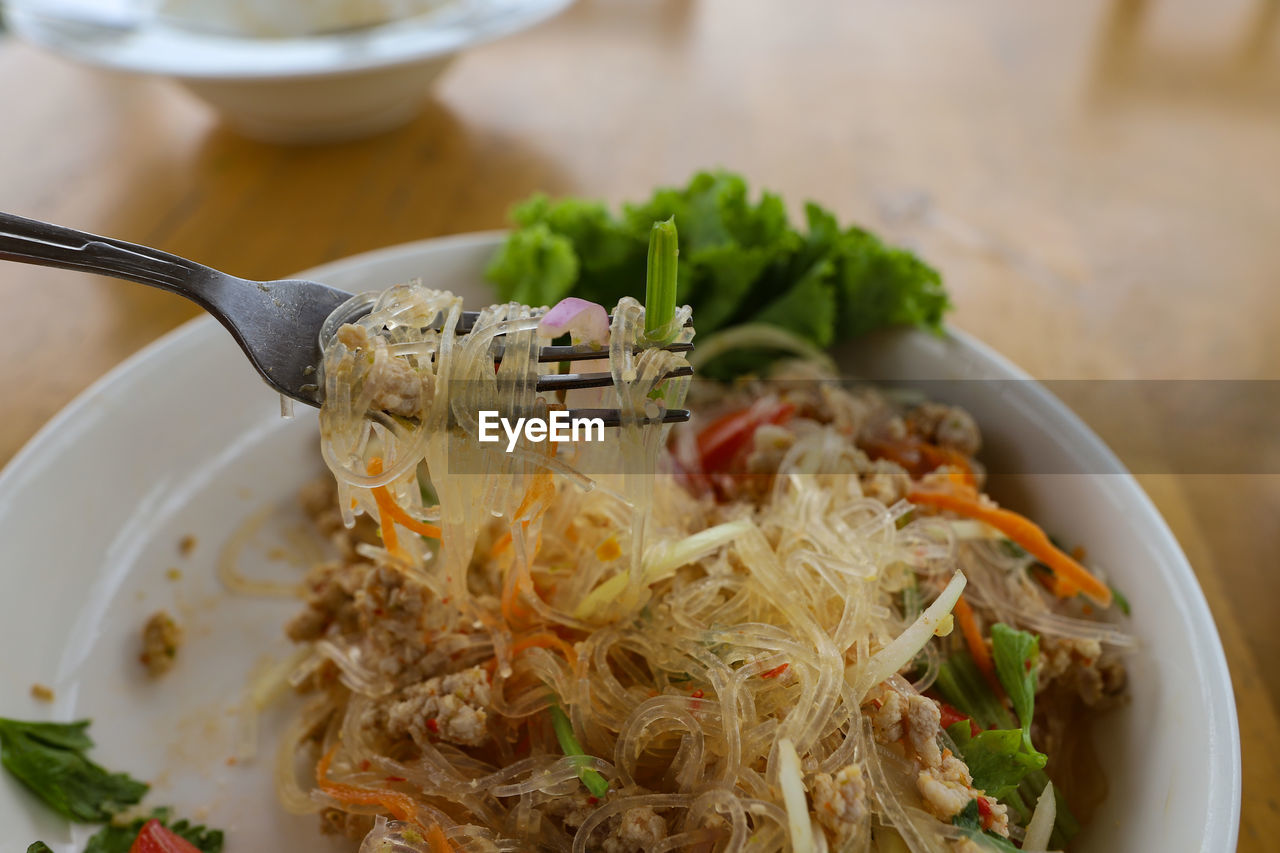 High angle view of  thai food spicy salad with glass noodle in bowl on table.