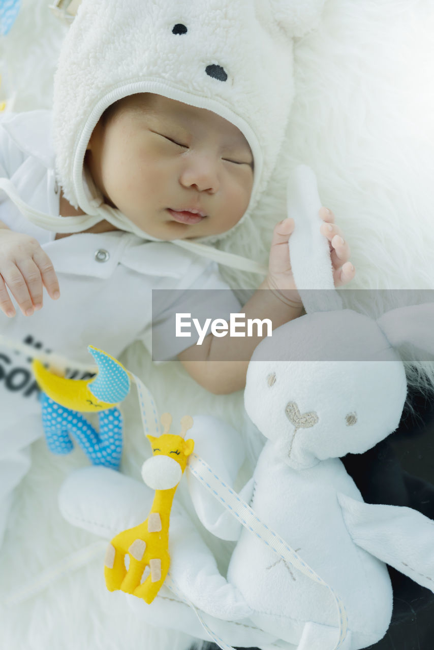 Cute baby boy sleeping with toy on bed at home