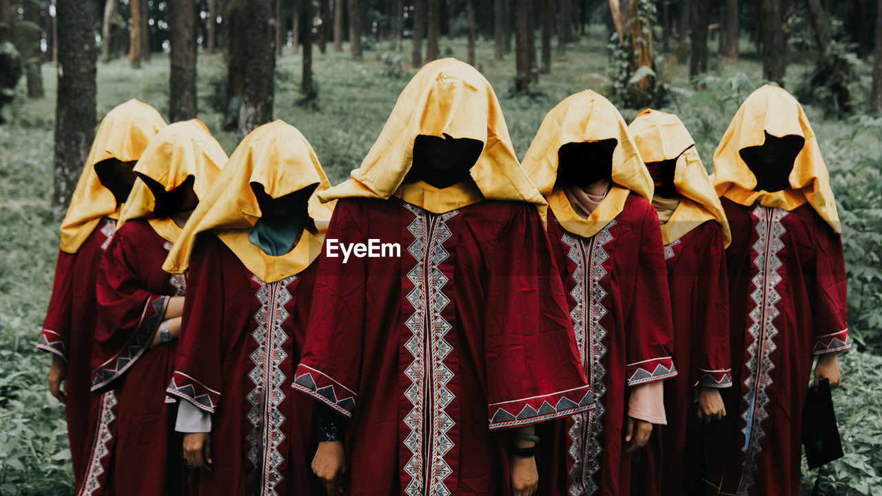 Spooky women standing against trees in forest